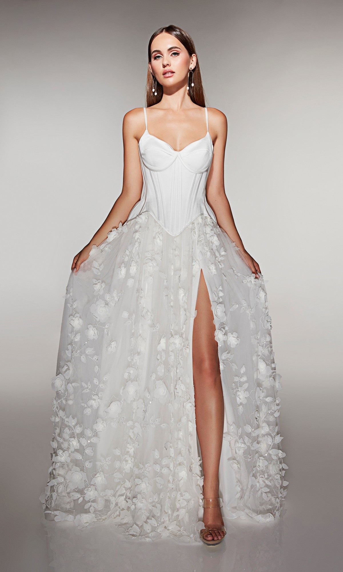 A woman models the Alyce 62072 long formal dress, which features a corset bodice, sheer 3D floral-lace appliques, and a high slit, standing against a plain background.